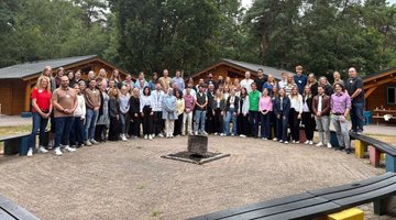 Das Foto zeigt die rund 60 Teilnehmenden der Projektfahrt nach Ysselsteyn auf dem zentralen Platz der Jugendbegegnungsstätte - vor den Blockhütten, die zur Übernachtung dienen.
